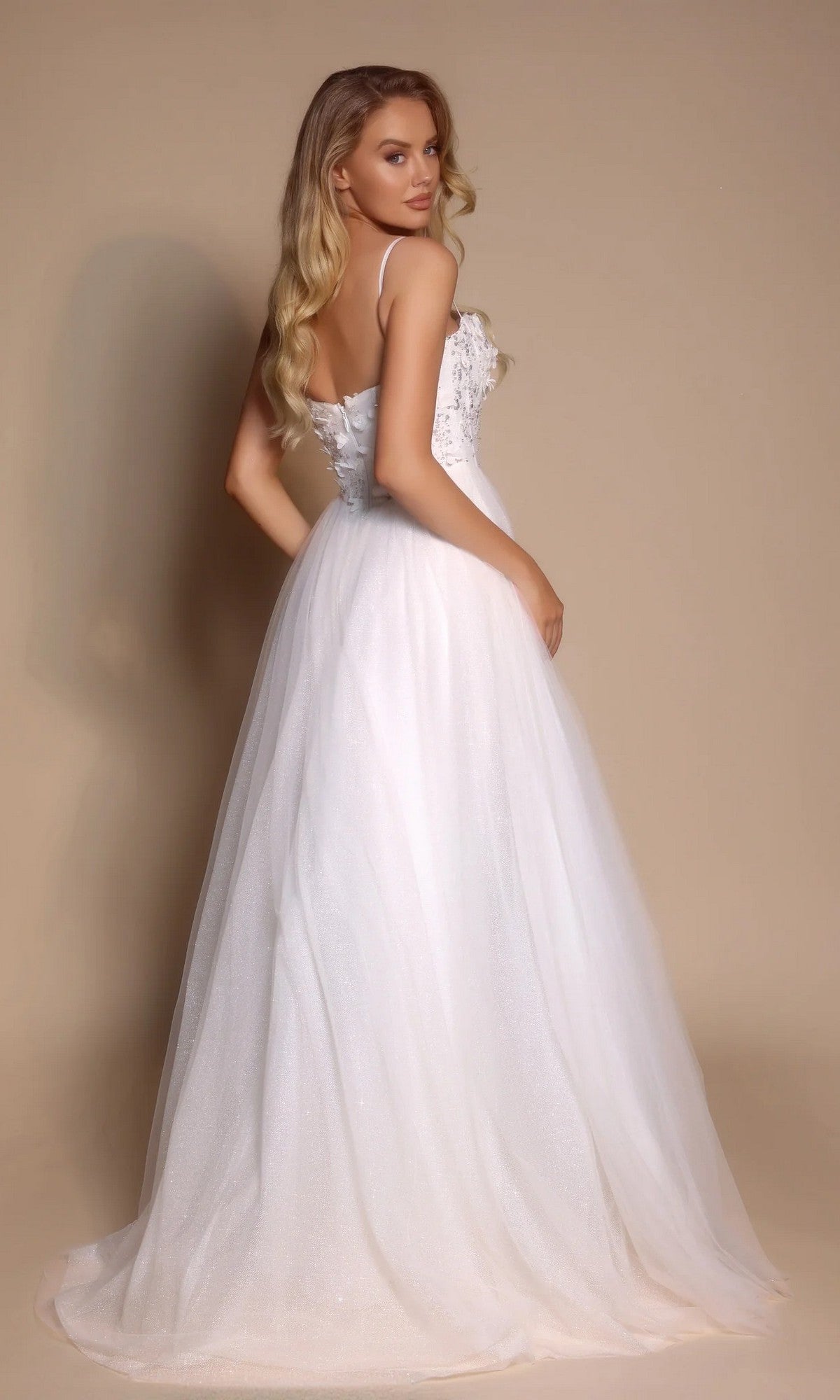 Woman in the Portia and Scarlett PS26146 Glitter Prom Ball Gown, featuring a boned-corset bodice and full glitter tulle skirt, poses gracefully against a plain beige background.